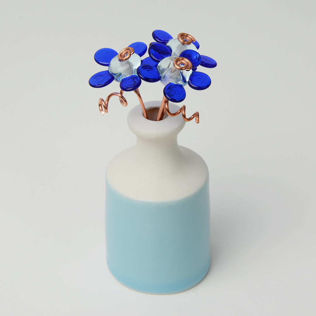 'True Blue' bouquet of three blue glass daisy flowers in a miniature bottle vase
