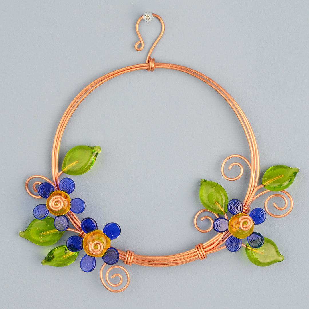 Miniature copper wreath with blue glass flowers and green glass leaves