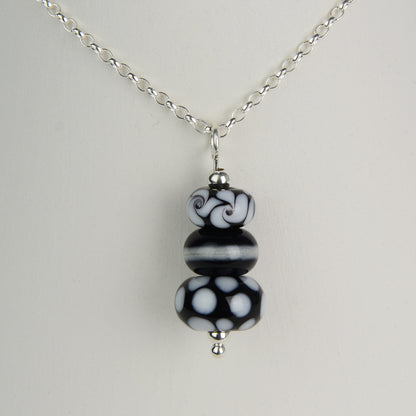 Three black and white glass beads making a pendant on silver chain