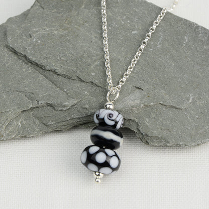 Three black and white glass beads making a pendant on silver chain