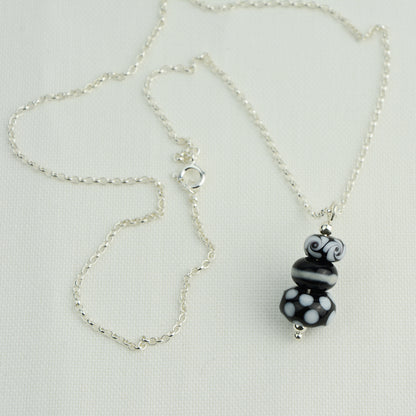 Three black and white glass beads making a pendant on silver chain