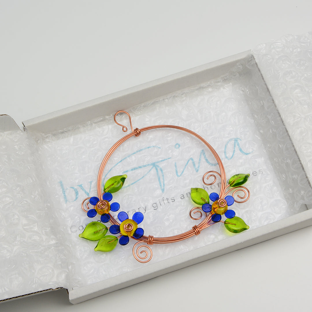 Miniature copper wreath with blue glass flowers and green glass leaves in white gift box
