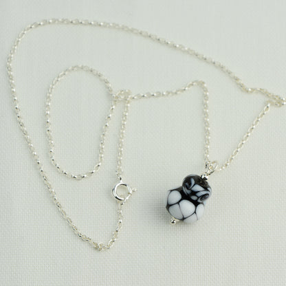 Two black and white glass beads making a pendant on silver chain