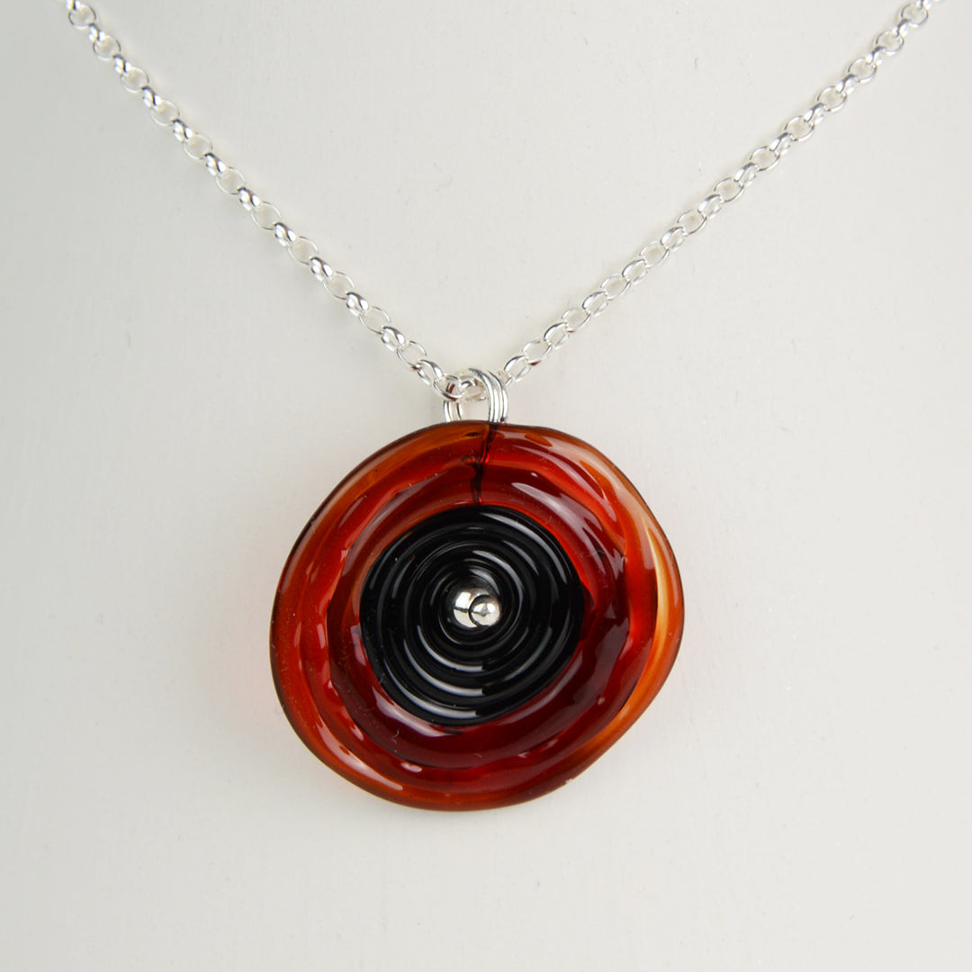 Spiral of red and black glass to replicate a poppy flower on a silver chain
