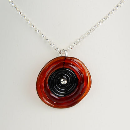 Spiral of red and black glass to replicate a poppy flower on a silver chain