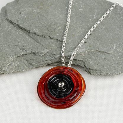 Spiral of red and black glass to replicate a poppy flower on a silver chain